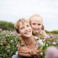Two smiling children on clover field
